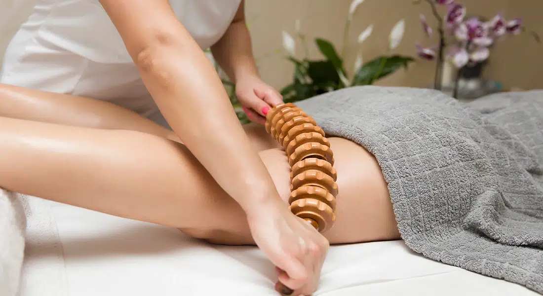 Massage avec rouleau en bois sur la jambe